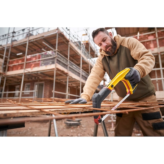 STANLEY 0-20-108 hacksaw cutting metal rods on construction site, side angle, worker wearing gloves.