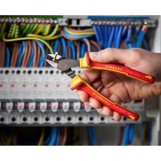 STANLEY 0-84-009 insulated diagonal cutting pliers held by hand, cutting wire in electrical panel.