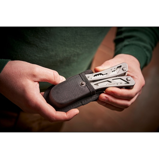 STANLEY 0-84-519 multitool in black case held in hands, close-up photo.