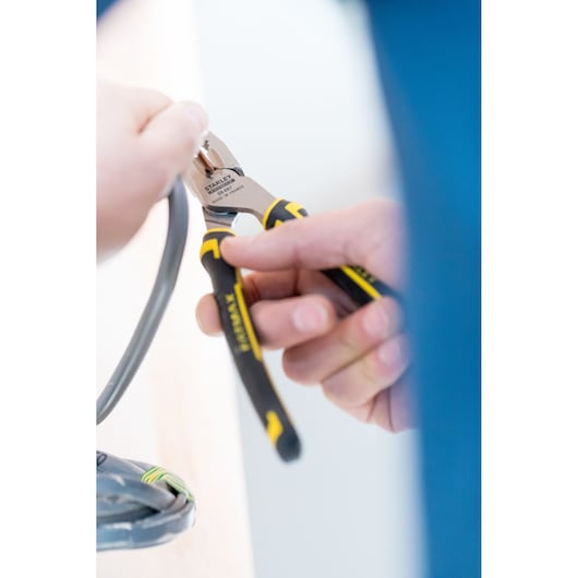 STANLEY 0-89-867 diagonal cutting pliers with black and yellow handles cutting a gray cable, close-up.