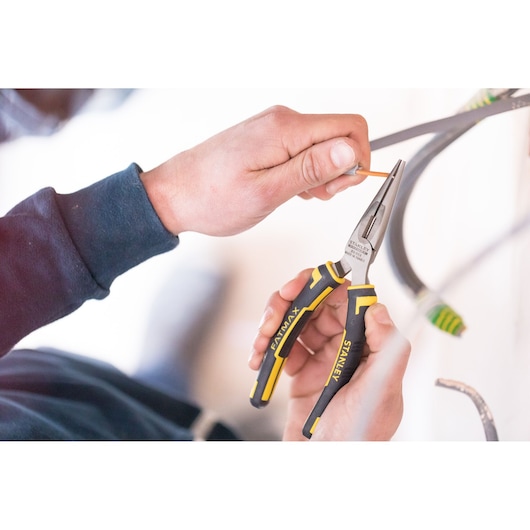 STANLEY 0-89-869 long nose pliers with yellow and black handle in use by hand, close-up photo.
