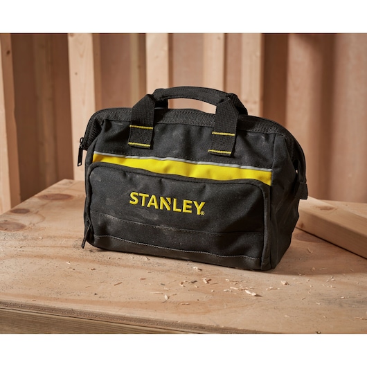 STANLEY 1-93-330 black and yellow tool bag with handles on a wooden workbench, front angle.