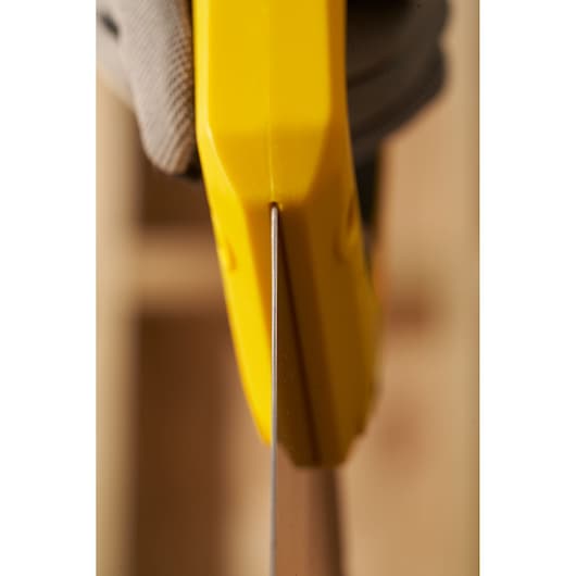Close-up side view of STANLEY 2-15-289 hand saw with yellow handle in use, focusing on blade.