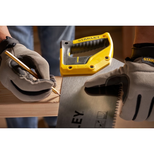 STANLEY 2-15-289 handsaw held by gloved hands marking wood, close-up side angle.
