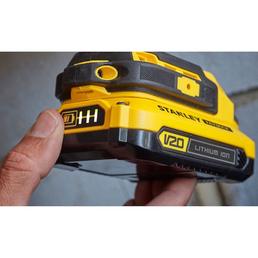Stanley SFMCD711B V20 Lithium Ion battery close-up, yellow and black casing, finger pressing indicator.