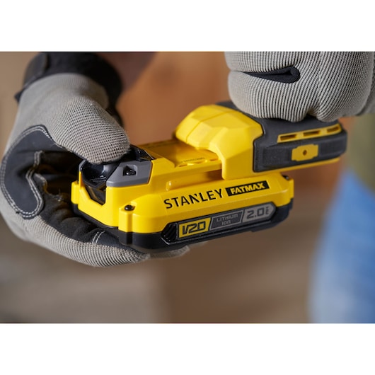 Photo of STANLEY SFMCF810B impact driver with yellow V20 FATMAX lithium-ion battery held by gloved hands.