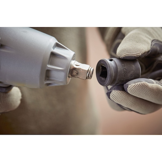 STANLEY SFMCF900B impact wrench close-up with gloved hands attaching socket.