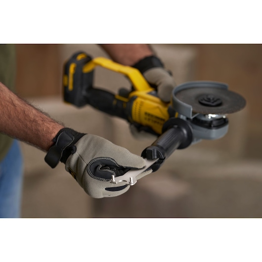 STANLEY SFMCG400B angle grinder held by gloved hands, close-up view during tool adjustment.