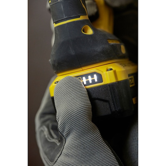 STANLEY SFMCH900B power tool close-up, battery indicator lit, glove pressing button, side angle.