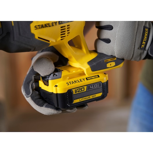 Photo of STANLEY SFMCS300B power tool with V20 4.0Ah lithium ion battery being held by gloved hands.