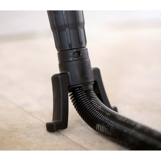 STANLEY SFMEE500S vacuum hose attachment close-up photography, black plastic connector with flexible hose on floor.