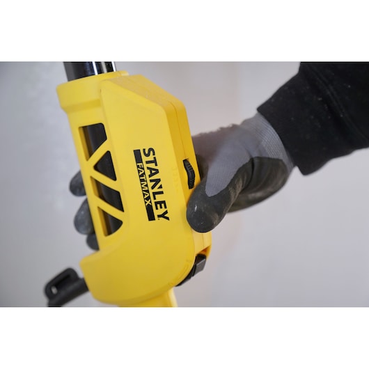 Photo of STANLEY SFMEE500S yellow tool handle with black FATMAX logo, gripped by gloved hand, close-up view.