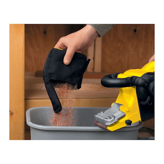 STANLEY STBS720 sander with dust bag emptied into bin, yellow tool visible, close-up angle.