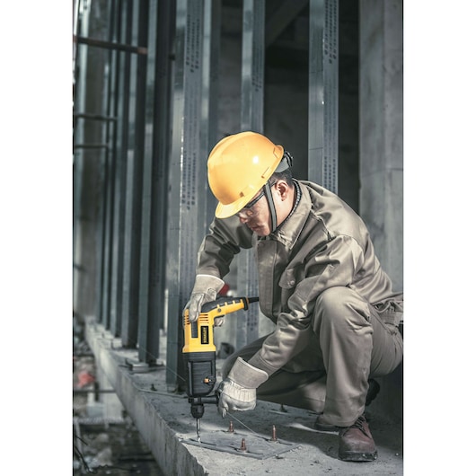 STANLEY STHR223K rotary hammer drill used on concrete at construction site, worker in safety gear.